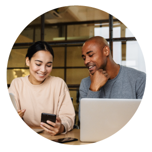 Two people looking at a phone while sitting on a desk.